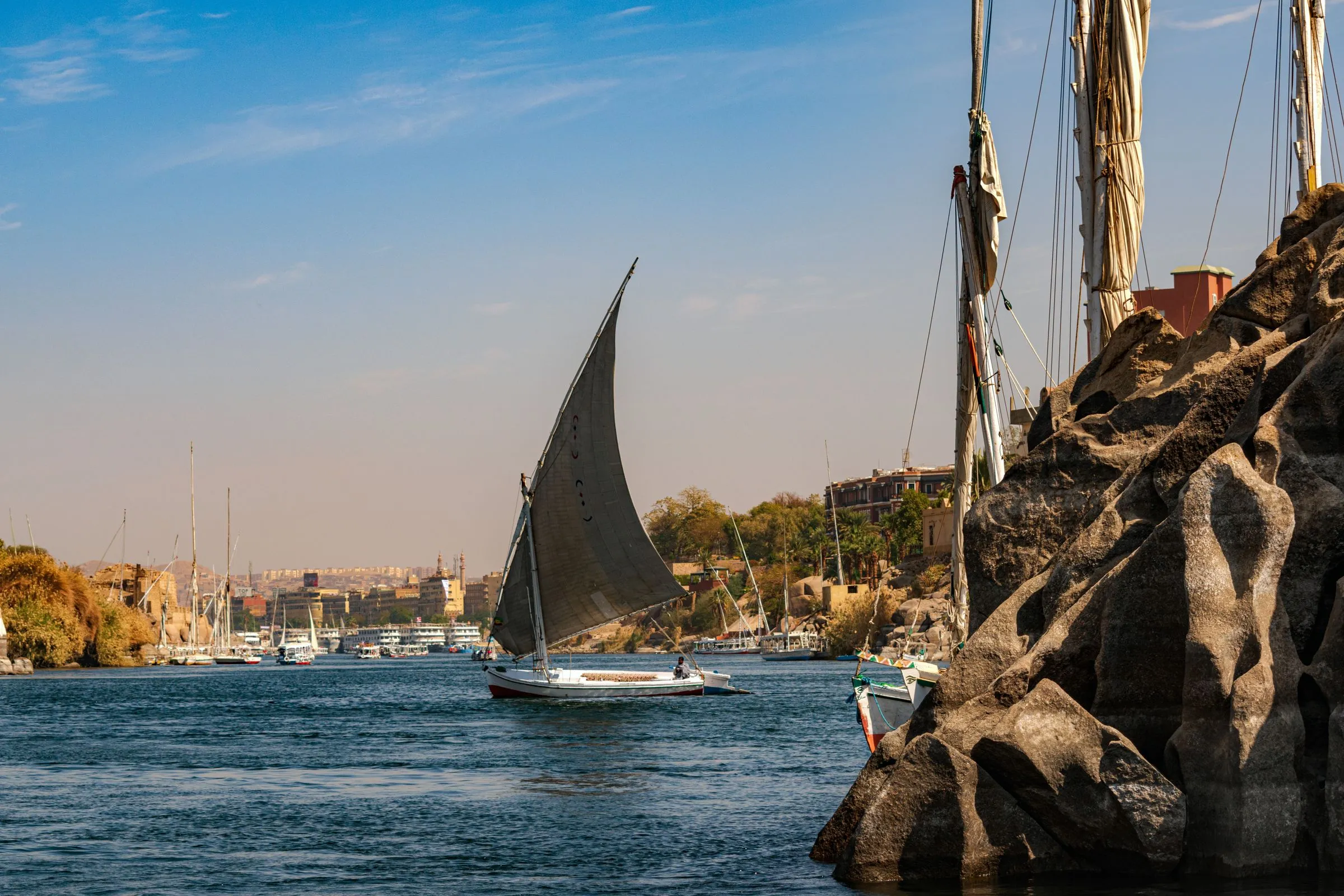A felucca sailing on the Nile past the granite rocks of Aswan, Egypt