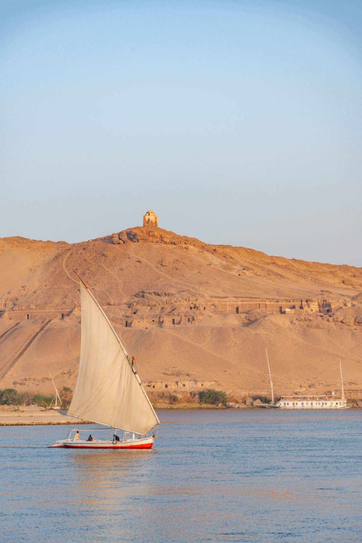 A felucca sailing the Nile below the desert hills of Aswan's west bank